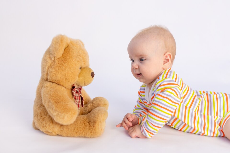نوزاد در حال لبخند زدن به عروسک در هنگام بازی